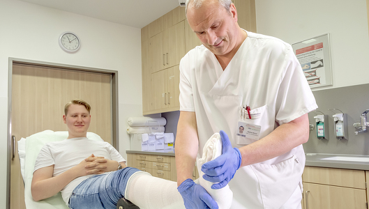 Ambulanzpfleger legt einen Gipsverband am Bein an