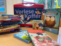 Ein roter Koffer von der Stiftung Lesen. Davor liegen viele Bücher.