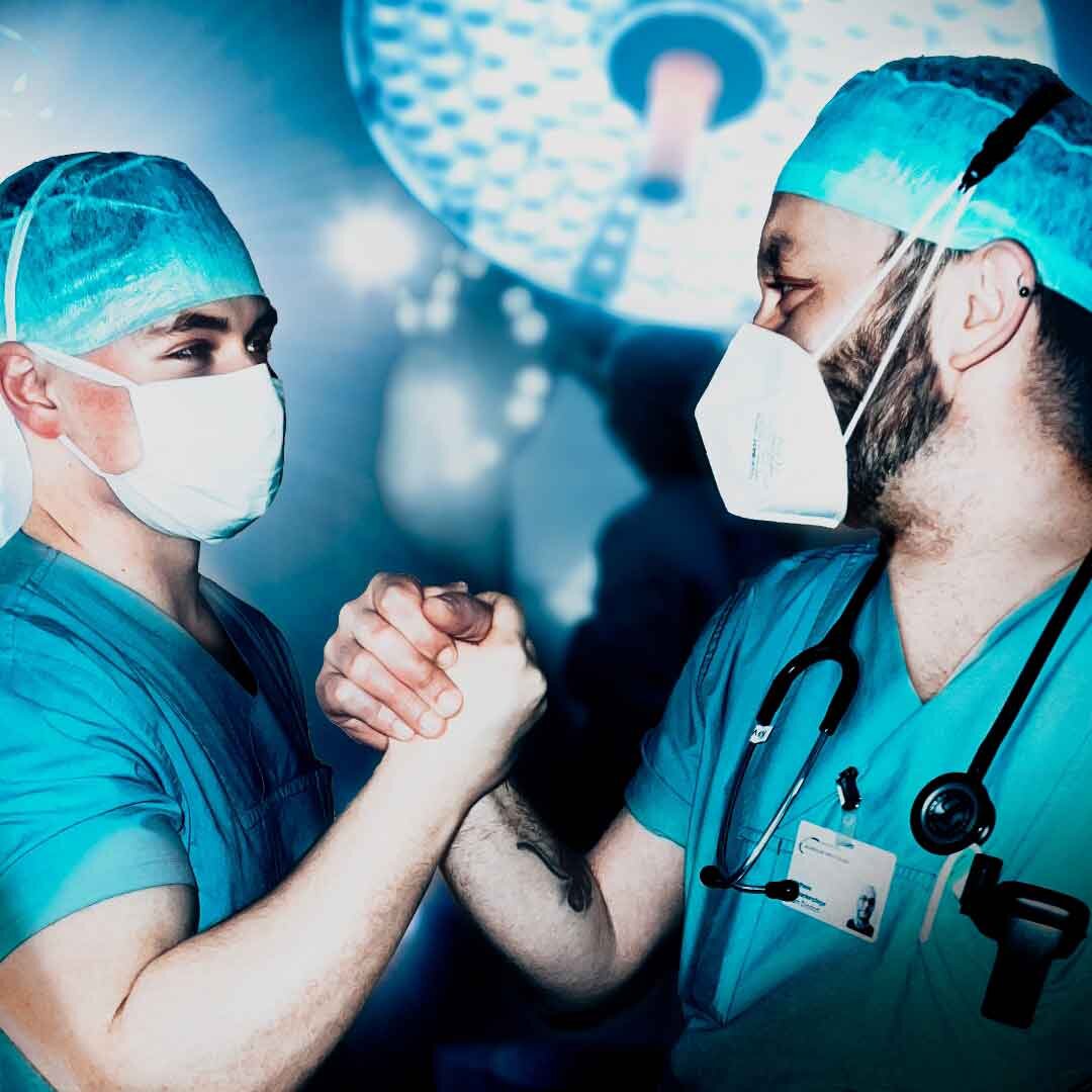 Zwei männliche OP-Pflegefachkräfte unterstützen sich bei der Arbeit im OP