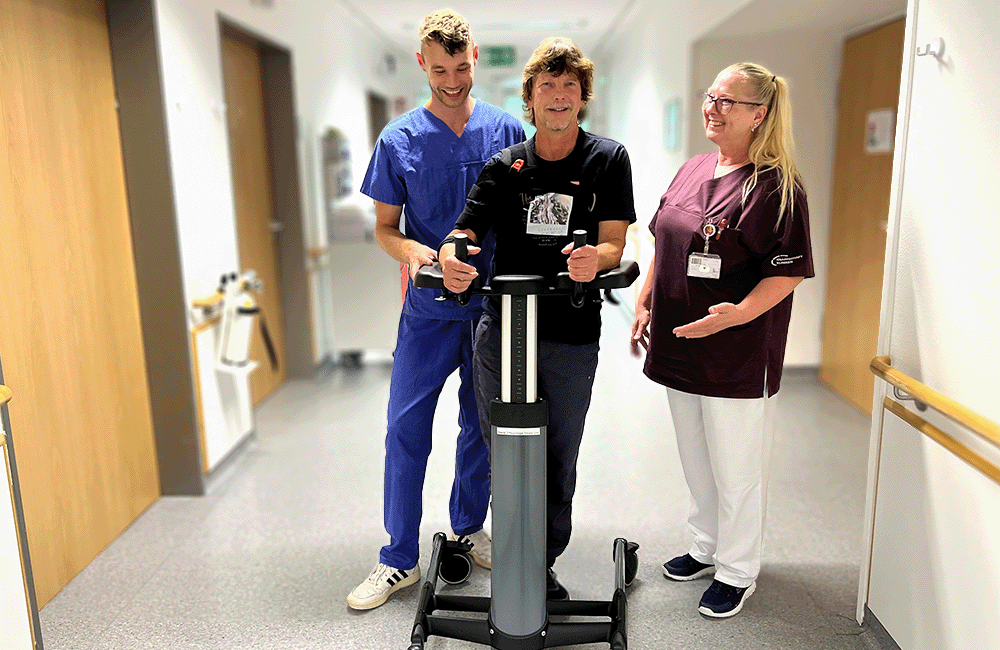 Ein Patient der Neurologischen Frühreha im Neurozentrum erhält Unterstützung bei Gehversuchen von einer Pflegekraft und einem Therapeuten
