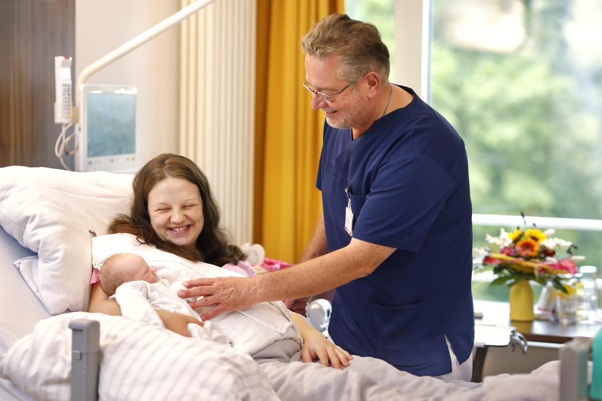 Dr. Thomas Heuser, Chefarzt der Klinik für Gynäkologie, Geburtshilfe - Brustzentrum mit einer Patientin und ihrem Baby nach der Geburt 