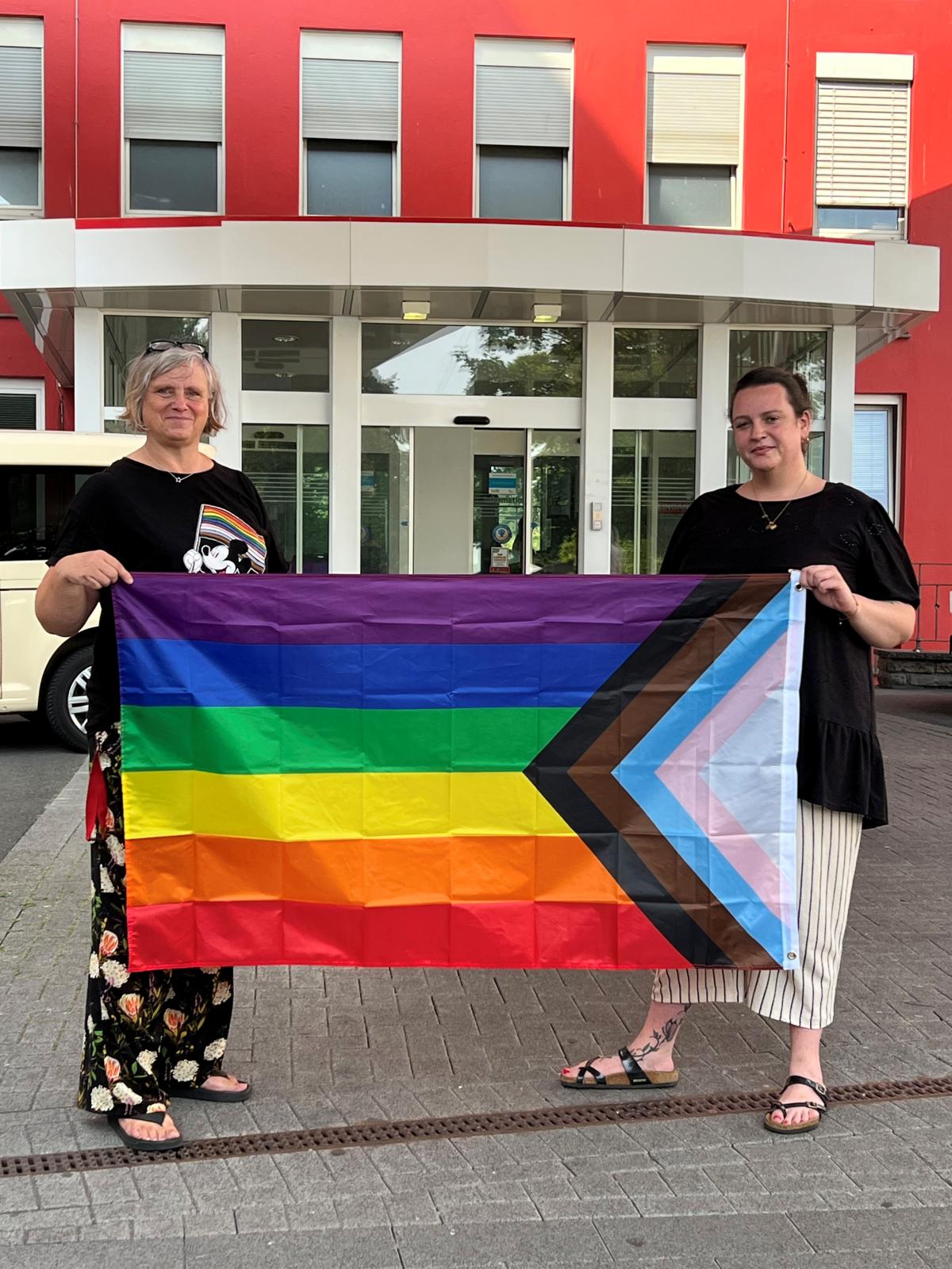 Die Gleichstellungsbeauftragten der Knappschaft Kliniken Westfalen, Beatrix Keifler(l.) und Michèle Olschewski hissen die Regenbogenflagge. Regenbogenflagge