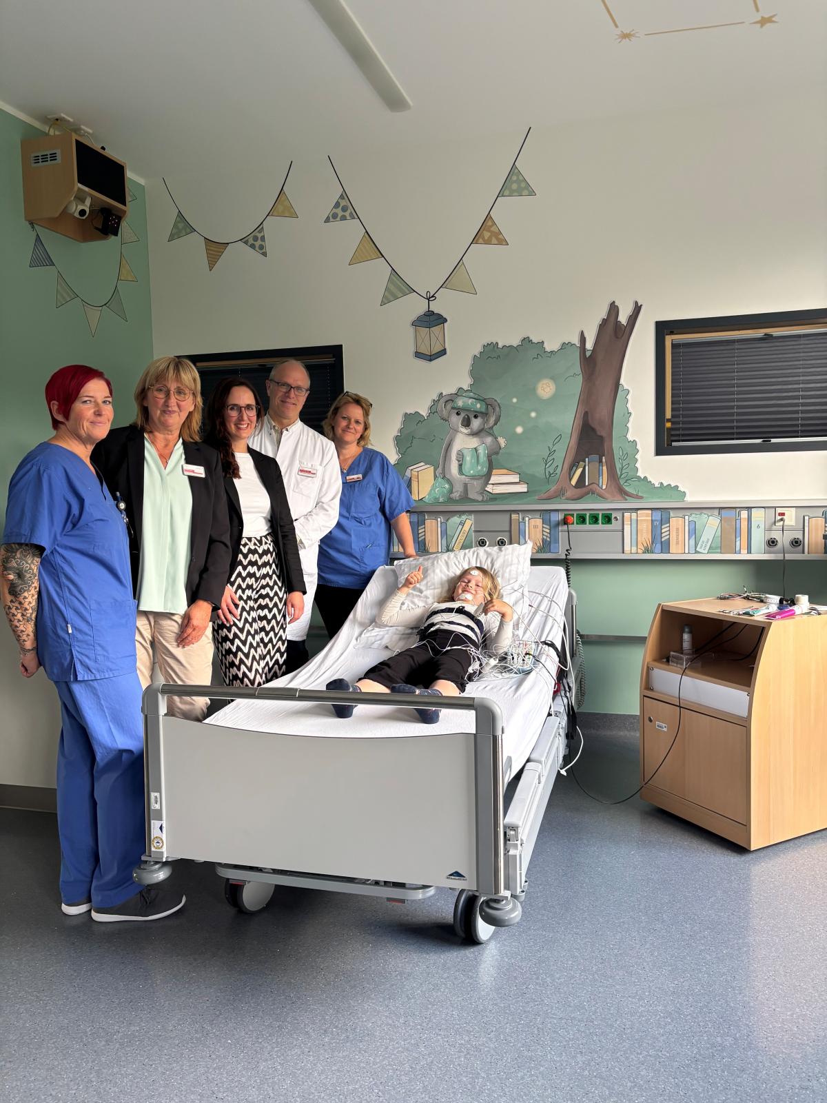 (v. l.) Jessica Klaßmann (Schlaflabor), Martina Koch (Pflegedirektorin), Daniela Derscheid (Geschäftsführerin), Dr. med. Mirco Kuhnigk (Chefarzt und Direktor der Kinderkliniken im Verbund der Knappschaft Kliniken), Brigitte Reißing (Stationsleitung) sowie Mia Reißing (Testschläferin im Schlaflabor). Das Kinder-Schlaflabor in Gelsenkirchen Buer